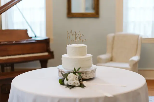 Two-tier white cake on a round table beside the piano