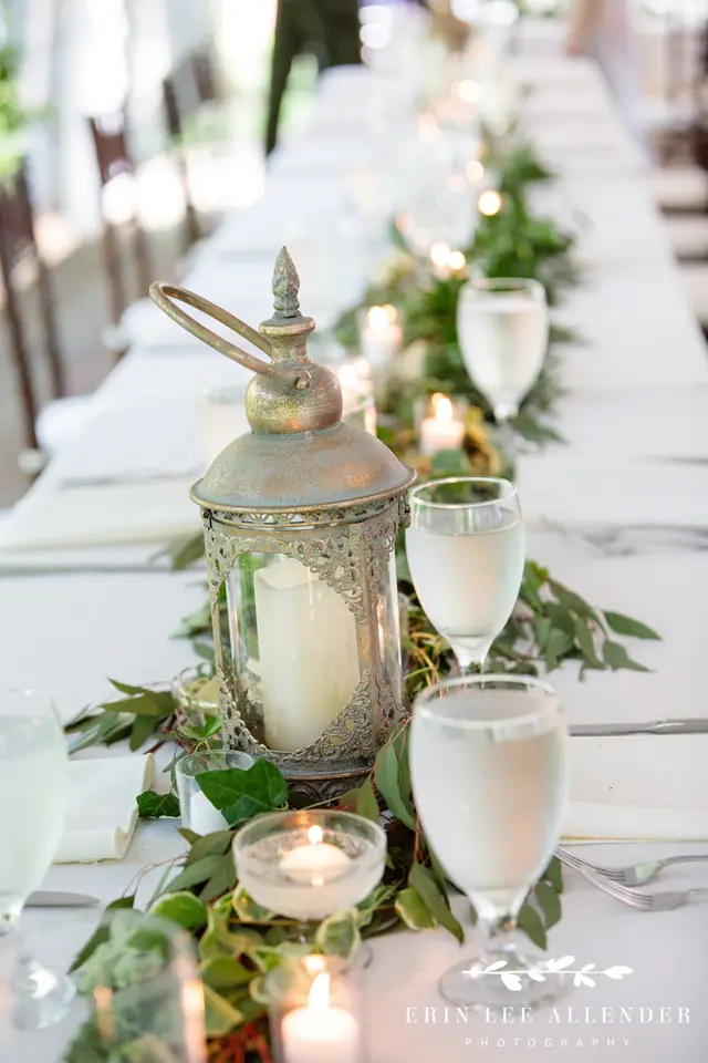 Lantern and water glasses on a long white reception table