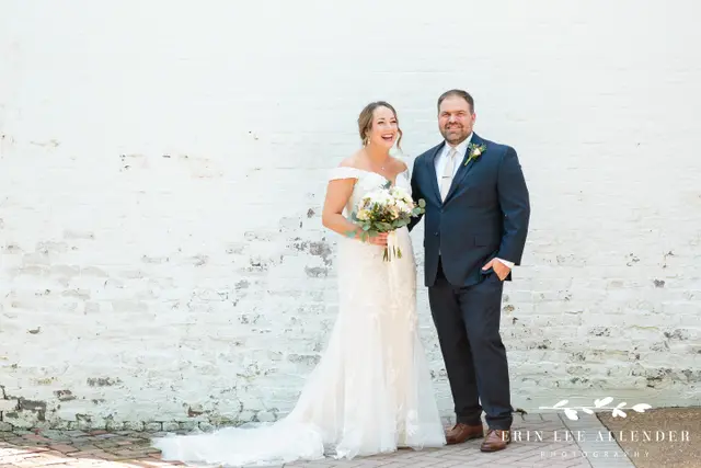Couple laughing in front of a whitewashed brick wall
