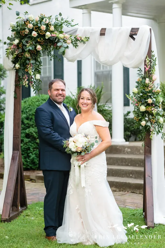Couple under a draped floral arbor at the front steps