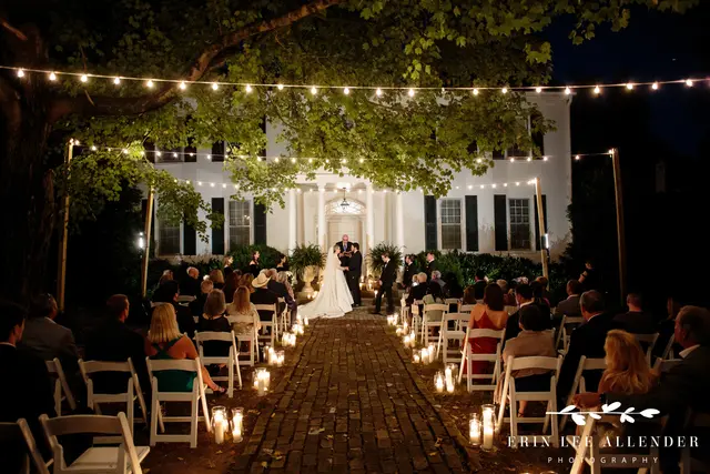 Candlelit evening ceremony under string lights in front of the mansion