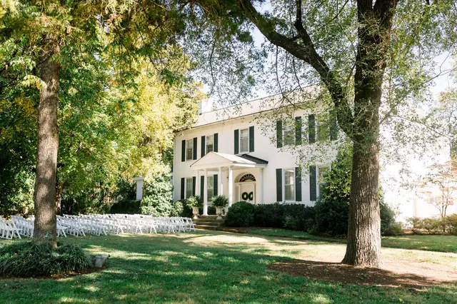 The white mansion with ceremony chairs set out on the front lawn