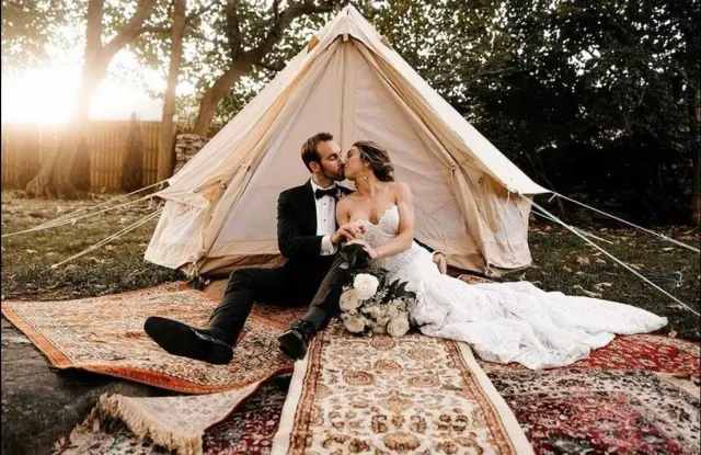 Couple on layered rugs in front of a canvas bell tent