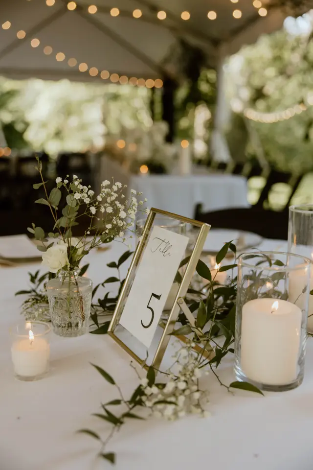 Table number five with candles and baby's breath under a tent