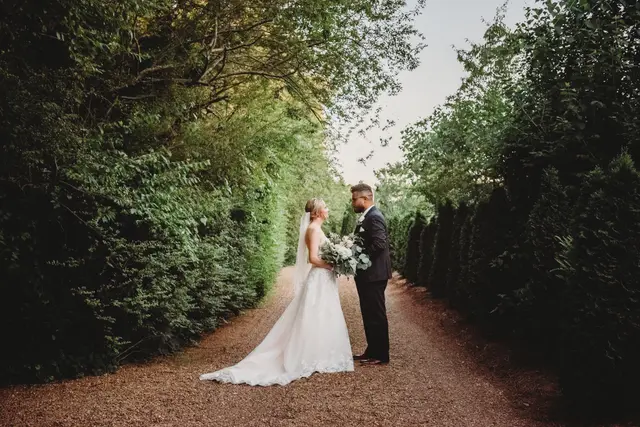 Couple kissing at the far end of the hedge-lined lane