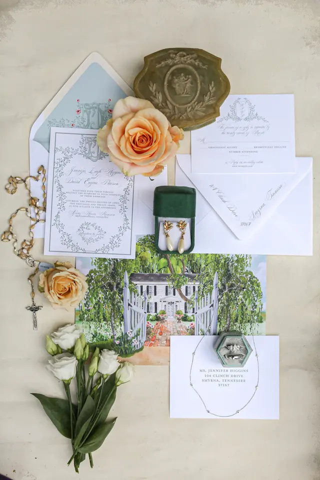 Invitation suite laid flat with roses and the rings