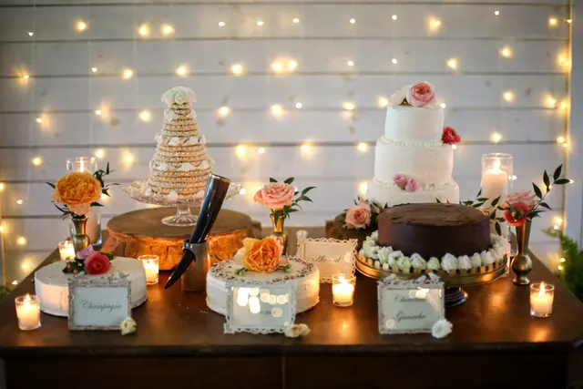 Dessert table of cakes and candles against a wall of lights
