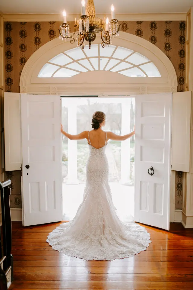 Bride at the open front doors under the brass chandelier