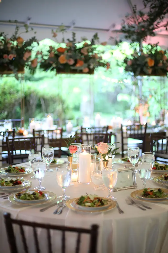 Reception tables set with salads beneath hanging flowers under a tent