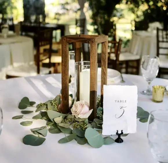 Table five centerpiece with a wooden lantern and eucalyptus
