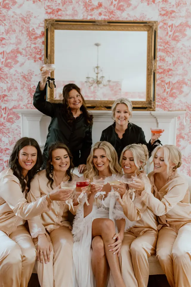 Bridesmaids in satin pajamas toasting in the toile room