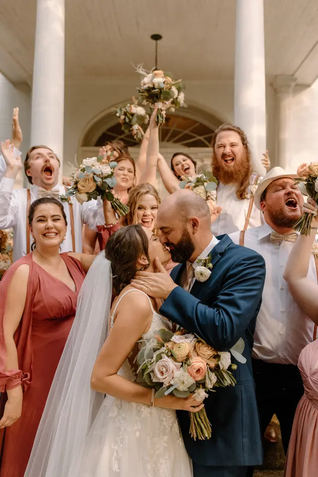 Wedding party cheering around the couple on the portico steps
