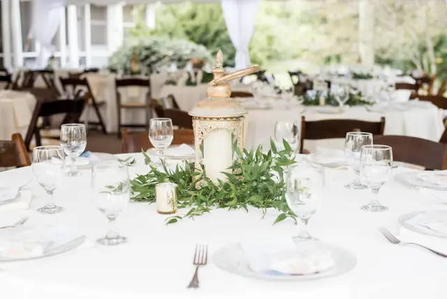 Reception table with stemware, white linens and a greenery runner