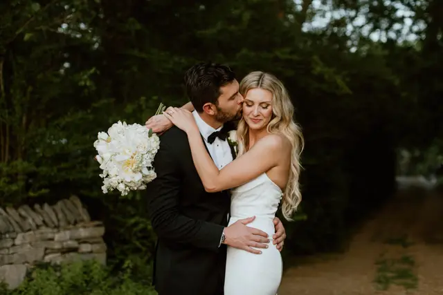 Couple embracing by a dry-stone wall at dusk