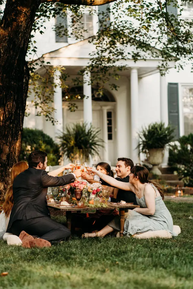 Small group dining at a low table on the lawn in front of the portico