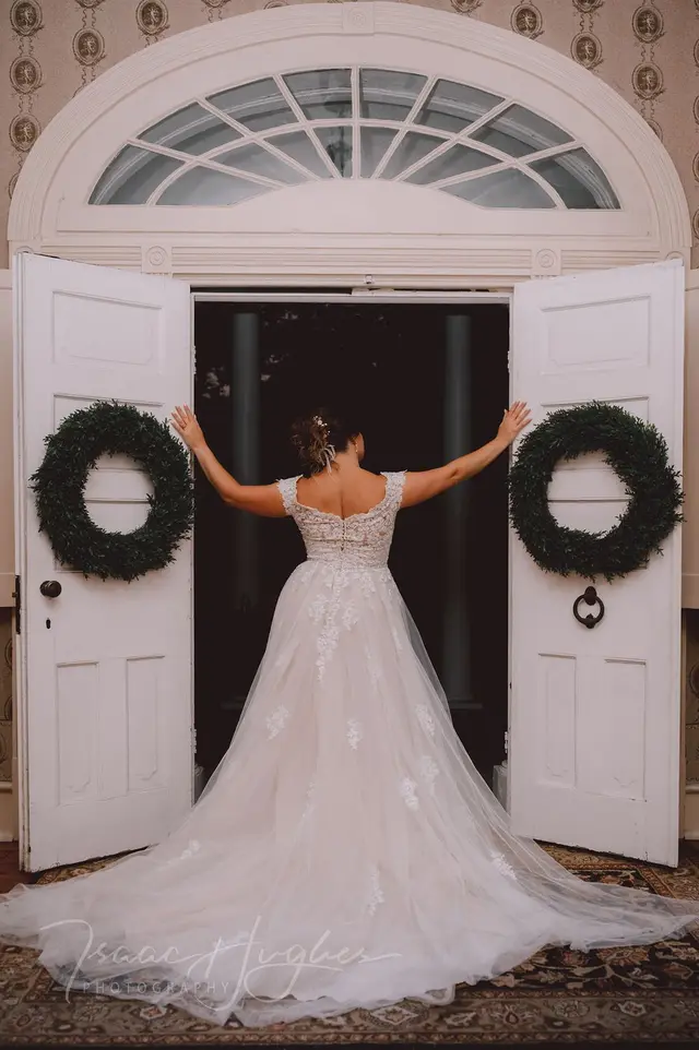 Bride opening the double front doors under the fanlight, wreaths on both doors