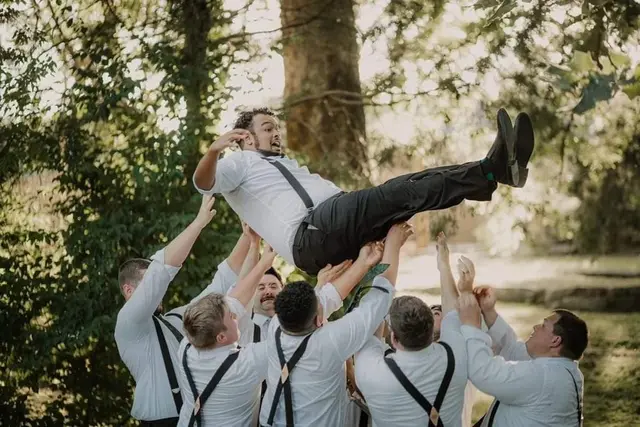 Groomsmen tossing the groom into the air