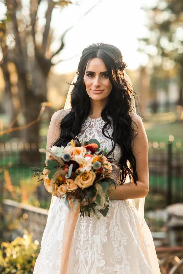 Bride holding an autumn bouquet in the golden-hour light