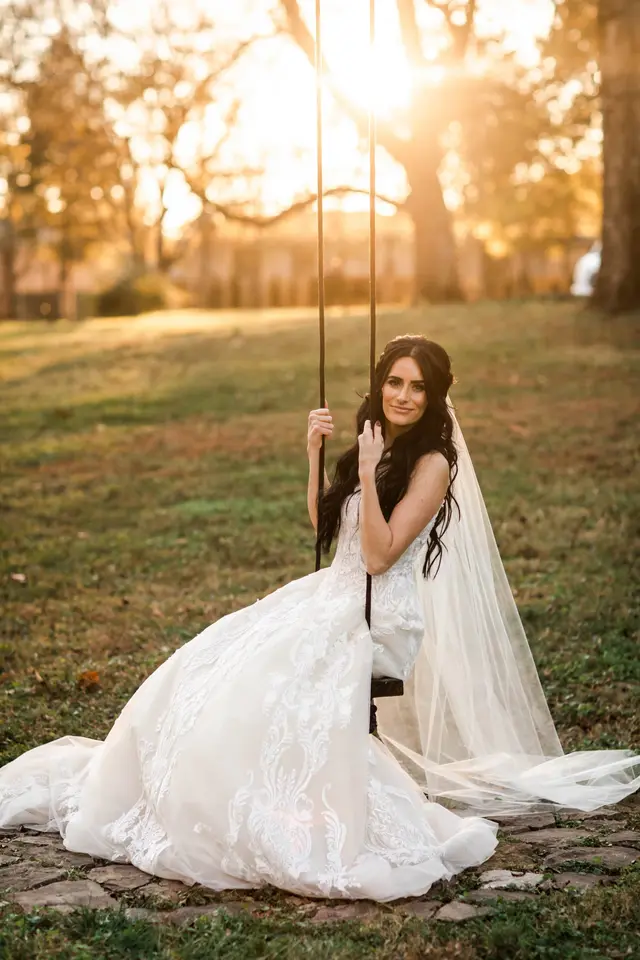 Bride on a rope swing hung from a tree at sunset