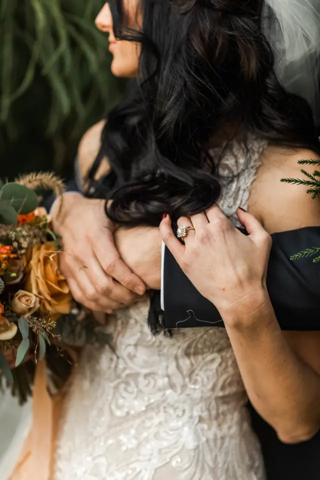 Close-up of a lace gown and an autumn bouquet in an embrace