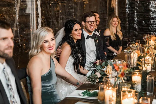 Bride and guests smiling at a candlelit reception table