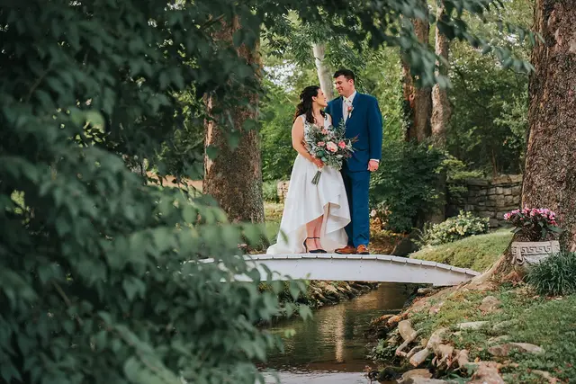 Couple standing on the white footbridge over the stream
