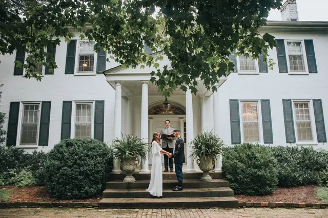 Couple saying their vows on the front steps with the officiant