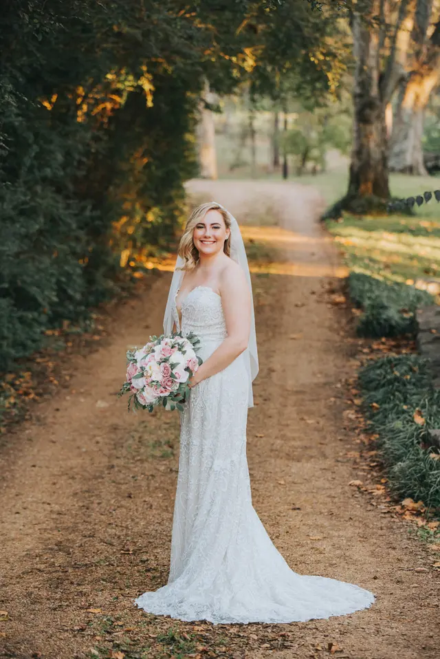 Bride alone on the gravel lane at sunset