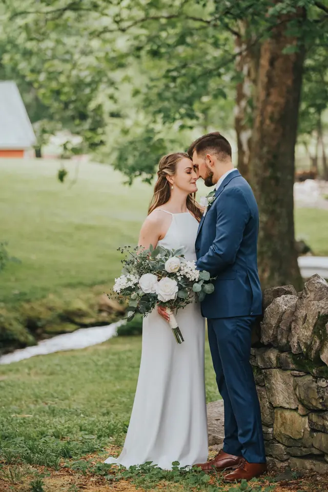 Couple touching foreheads by the stone wall along the stream