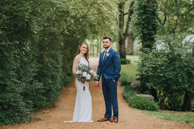 Couple holding hands halfway down the hedge-lined lane