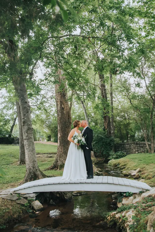 Couple kissing on the footbridge in full summer green